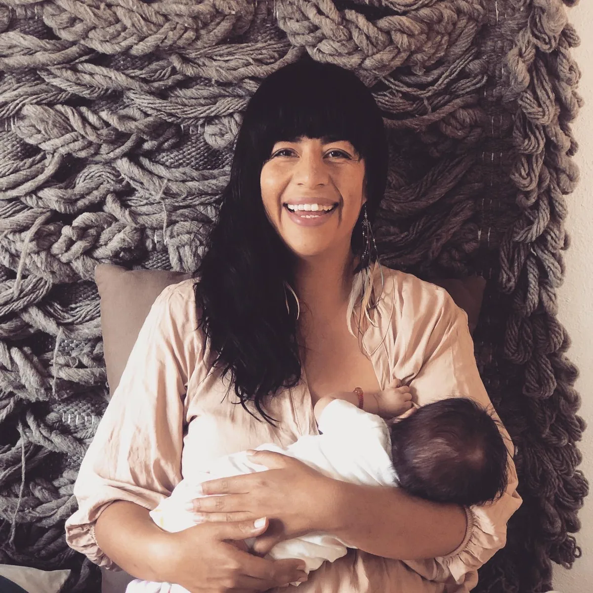 Una madre sonríe mientras amamanta a su bebé